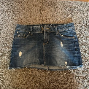 Blå jeanskjol från Esprit - Snygg blå jeanskjol från Esprit med slitna detaljer och rå kant nertill. Klassisk femficksmodell med broderade bakfickor och dragkedja framtill. Perfekt för dig som gillar en cool och avslappnad stil. Också köpte vintage i barcelona och finns inte att köpa längre