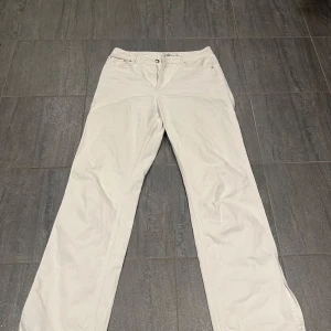 Vita raka jeans från NA-KD, strl 38 - Snygga vita jeans från NA-KD i rak modell med slits. Byxorna har normal midja, dragkedja och knapp framtill. Perfekta till sneakers eller boots för en clean look.