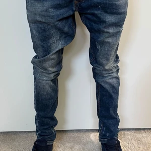 Mörkblå jeans med slitningar - Random jeans, W32 L30 har ett litet hål på benet