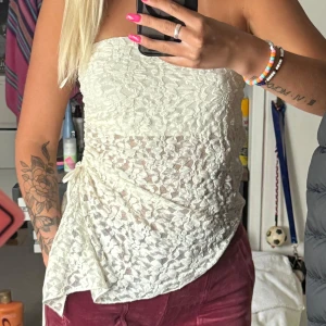 Vit spets tubtopp med knyt - Säljer en vit tubtopp i spets med asymmetrisk nederkant och knyt i sidan. Aldrig använd 