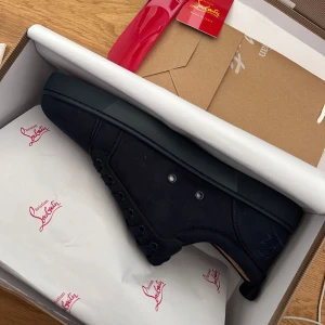 Mörkblå  Christian Louboutin - Stilrena sneakers från Christian Louboutin i mocka med klassisk röd sula och diskret logga på hälen. Skorna har snörning, rund tå och platt sula. Perfekta för dig som vill ha en lyxig och clean look med en ikonisk touch.