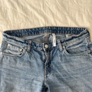 Ljusblå raka jeans från Weekday - Säljer ett par klassiska ljusblå jeans från Weekday med raka ben. Jeansen har normal passform, bälteshällor och snygga kontrastsömmar. Perfekta till sneakers eller boots för en avslappnad look.