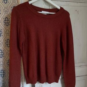 Vinröd stickad tröja från Vila - En enkel och snygg vinröd stickad tröja från Vila. Tröjan har rund halsringning, långa ärmar och ribbade muddar vid hals, ärmslut och nederkant. Perfekt för lager-på-lager och passar till både jeans och kjol.