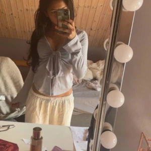 Ljusgrå omlottopp med knyt från Gina❤️ - Supersöt ljusgrå omlottopp med knyt framtill och v-ringning. Toppen är croppad och har långa ärmar, perfekt för en trendig och chill look. Tunn och mjuk i materialet, passar till både jeans och kjol.