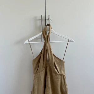 Beige omlott topp med halterneck - Snygg beige topp med omlott-detalj och halterneck. Jätte fin topp som man kan ha på fest eller en fin middag. Knappt använd så i mycket bra skick. 