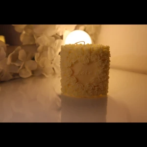 Love Letter Rose Candle - A romantic rectangular candle framed with delicately sculpted roses, featuring the word "Love" embossed in the center. Its soft vanilla hue makes it a timeless piece -ideal for weddings, anniversaries, or heartfelt gifts. H:77mm B:75mm