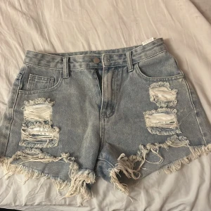 Ljusblå jeansshorts med fransar - Säljer ett par ljusblå jeansshorts med hög midja och fina slitna detaljer framtill. Dessa är från shein men är jätte fina.