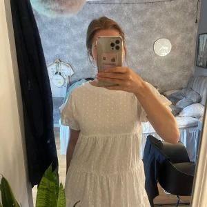 Vit broderad kortklänning med volang - Superfin vit kortklänning i bomull med broderade blommor och volangärmar. Klänningen har en luftig passform, rund halsringning och dragkedja bak. Har andvänts 1 gång och är i mycket bra skick! Älskar!!
