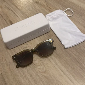 Chimi solglasögon 04 grön - Säljer ett par stilrena olivgröna solglasögon från Chimi. Modellen har en klassisk, något fyrkantig form och levereras med originalvitt etui och tygpåse. Perfekta för dig som vill ha en clean och modern look. Modell 04