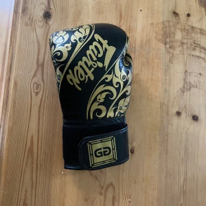 Fairtex Glory BGLG2 Black Kickboxing Glove - Thaiboxningshandskar 12 OZ, genuint läder, handgjorda i Thailand. Collab mellan Fairtex och glory. Relativt använda men fortfarande i perfekt skick. Bara använda på säck inte sparrats med dessa.