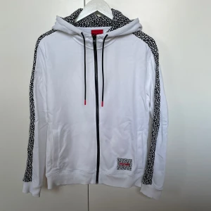 Hugo Boss kofta  - Vit hoodie från Hugo Boss med svarta detaljer.                             Nyskick, oanvänd.                                                                           Strl XS men sitter som S