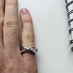 Handgjord Silver Ring I Flätad Design - Unik Handgjord ring i silverfärg med tre band som korsar varandra i en flätad och modern design. Ringen har en stilren och minimalistisk look som passar perfekt för dig som gillar enkla men coola accessoarer. Ca 17 mm i diameter 