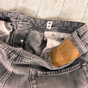 Grå jeans från Jack & Jones, straight fit - Snygga grå jeans från Jack & Jones i klassisk straight fit. Jeansen har fem fickor, knäppning med knappar och en cool tvättad look. Perfekta till sneakers och hoodie för en chill stil.