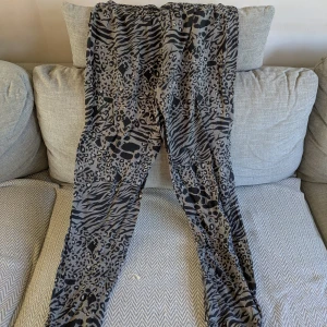 Grå leopard- och zebramönstrade tunna byxor från Think positive - Gråa mycket tunna och luftiga byxor med coolt leopard- och zebramönster. Perfekt en varm sommardag. Byxorna har resår i midjan. Jag är ca 170 cm för referens. Vid köp av flera klädesplagg av mig samfraktar jag såklart!