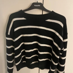 Svartvit randig stickad tröja KappAhl - Snygg svart stickad tröja med vita horisontella ränder från KappAhl. Tröjan har en avslappnad passform, rund halsringning och långa ärmar. Perfekt för dig som gillar klassisk stil med en modern twist.