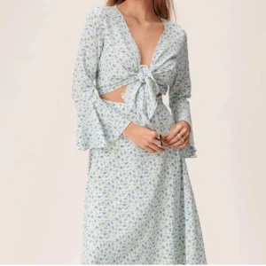 Blommig omlottklänning från Adoore - En super fin Adoore klänning som är vit med blåa blommor. Har använt den en gång så den är som ny. 