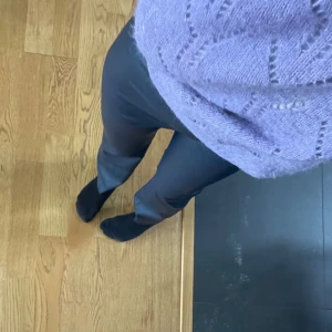 Svarta bootcut byxor i skinnimitation - Säljer ett par svarta, högmidjade byxor i skinnimitation med bootcut-snitt. Byxorna har en clean look utan synliga fickor eller dragkedjor och sitter tajt upptill med utsvängda ben. Passar allt.