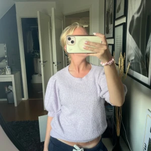 Ljuslila stickad tröja Vero Moda - Superfin ljuslila stickad tröja från Vero Moda med puffiga korta ärmar och rund hals. Mjuk och mysig känsla, perfekt till jeans eller kjol. Tröjan har en lite croppad passform och ribbade detaljer vid ärmslut och nederkant.