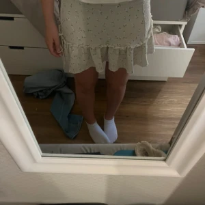 Ljusblommig volangkjol - Supersöt kort kjol i ljus färg med små blommor och volangkant. Kjolen har en feminin och flowy passform som ger en romantisk vibe. Perfekt för varma dagar och lätt att matcha med en enkel topp.