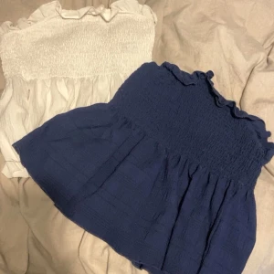Två volangiga bandeau toppar - Säljer två bandeau toppar med volangkant upptill, en i marinblått och en i vitt. Båda för 100 kr och en för 50, båda är i storlek S och knappast använts