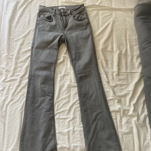 Grå bootcut jeans från Gina Tricot - Snygga grå jeans från Gina tricoti bootcut-modell. Jeansen har klassisk femficksdesign, bälteshällor och dragkedjegylf. Materialet är mjukt och stretchigt jeans, perfekt för en chill och trendig look.