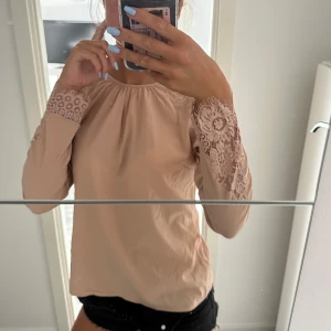 Blus - Säljer en beige blus med långa ärmar och snygga spetsdetaljer vid ärmsluten och längs ärmarna. Storlek m men passar S med. Skriv för fler bilder💗