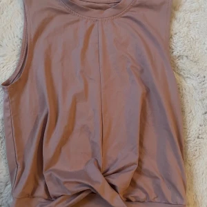 Ljuslila ärmlös linnetopp Oxide - Säljer en ljuslila ärmlös linnetopp från Oxide. Toppen har en enkel och clean design med en liten twist framtill vid nederkanten. Perfekt för dig som gillar en chill och stilren look.