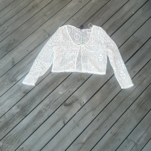 Vit virkad top från H&M Divided - Superfin vit virkad topp från H&M Divided. Croppad modell med långa ärmar och knyt framtill. Toppens mönster är öppet och ger en luftig känsla, perfekt att slänga över ett linne eller klänning. Tillverkad i 100% polyester. Vet att det står L på plagget men skulle inte säga att det stämmer snarare s-m om man inte vill ha en mer åtsittande modell 