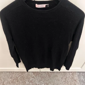Svart stickad tröja Jacqueline - En klassisk svart stickad tröja från Jacqueline Stockholm. Tröjan har rund halsringning och långa ärmar, perfekt för vardags-look. Enkel och stilren design som funkar till allt. Mjuk och skön känsla.