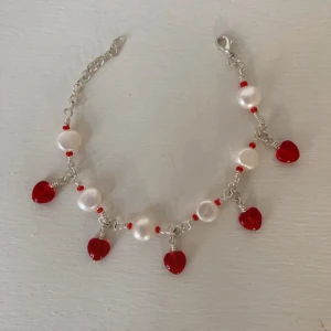 Armband med pärlor och röda hjärtan - Supergulligt armband med äkta pärlor och små röda hjärtan i glas. Jag har gjort armbandet själv. Skriv gärna om du skulle vilja specialbeställa ett!💕