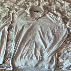 Ljusgrå half zip tröja Dressmann - Superskön ljusgrå tröja från Dressmann i storlek L, tillverkad i mjuk Supima-bomull. Tröjan har en stilren half zip-dragkedja vid kragen och långa ärmar. Perfekt för lager-på-lager och enkel att matcha med jeans eller chinos.