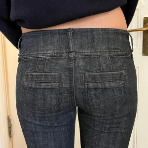 lågmidjade bootcut jeansbyxor - Snygga lowwaist jeansbyxor med bootcut-snitt och låg midja. Byxorna har diskreta bakfickor med lock och klassisk dragkedja framtill. Materialet är jeans med en lätt stretchig känsla, perfekta för en trendig och avslappnad look.
