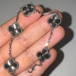 Silverfärgat armband med blommor - Snyggt armband i silverfärg med flera fyrklöverformade blommor som har fina detaljer och pärlkant runt varje blomma. Länken är tunn och smidig med ett klassiskt lås. Perfekt accessoar för att lyfta din outfit med en elegant touch.