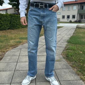 Levi's 501 ljusblå jeans straight fit - Klassiska Levi's 501 jeans i ljusblå tvätt med raka ben och normal passform. Jeansen har fem fickor, knappgylf och är tillverkade i slitstarkt bomullsjeans. Perfekta för en avslappnad och tidlös stil.