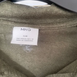 Olivgrön pikétröja från Mango - Säljer en olivgrön pikétröja från MNG i slim fit. Använd 1 gång. I linne material