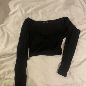 Svart långärmad topp  - Säljer stilren svart långärmad topp som är rynkad framtill . Toppen har en v-ringad design och är croppad. Perfekt för att matcha med både jeans och kjol.