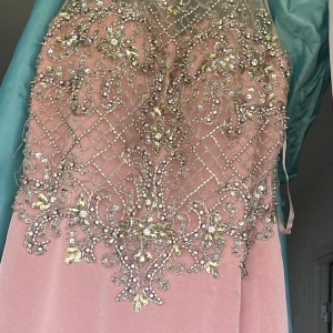 Rosa klänning med glittriga detaljer - Elegant rosa klänning med fantastiska glittriga detaljer och broderier i silver. Perfekt för speciella tillfällen med sin lyxiga känsla och vackra design.