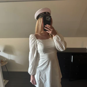 Vit klänning från Nelly - Säljer en stilren vit klänning från Nelly med långa ärmar och en fyrkantig urringning. Klänningen har en dragkedja i ryggen och är perfekt för studentfirandet. Den är i storlek EU 36. (aldrig använd) 💞💞jag brukar ha S/M🥰