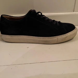 Myrqvist Navy sneakers i mocka - Snygga navy sneakers i mocka med rund tå och snörning. Perfekta för en stilren look. De har en vit sula som ger en fin kontrast till det svarta.
