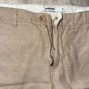 Beige shorts från Kappahl - Snygga beige shorts från Kappahl i linne. De har en dragkedja och knapp framtill samt hällor för bälte. Perfekta för varma sommardagar! Kom med bud 