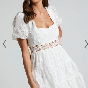 Vit spetsklänning från Showpo - Säljer en söt vit klänning från Showpo med spetsdetaljer och broderade blommor. Klänningen har korta puffärmar och en öppen rygg med knytband. 💖