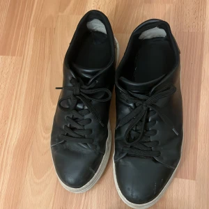 Svarta sneakers från Selected Homme - Snygga svarta sneakers från Selected Homme med klassisk snörning och vit sula. . Skorna har gått sönder med tyget inne i skorna men annars i bra skick. Kan gå ner i pris