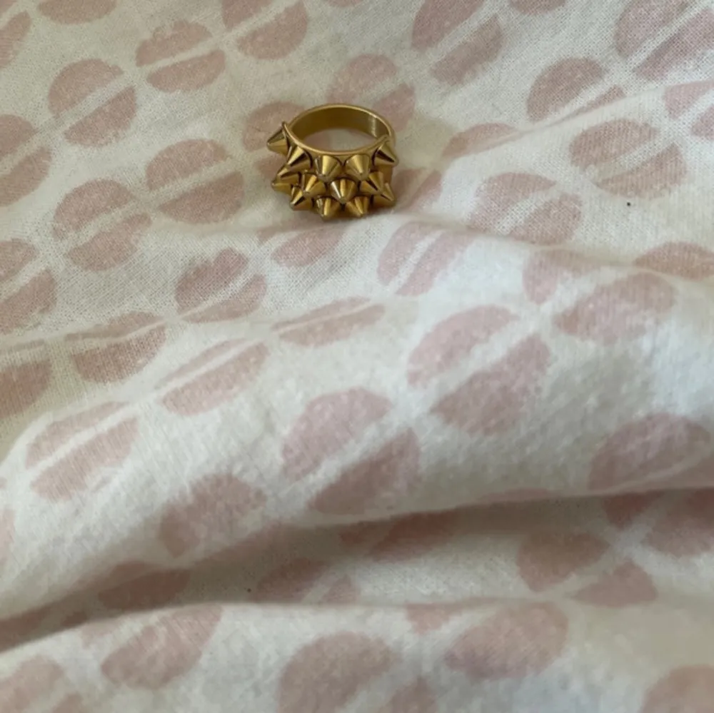 Snygg guldfärgad ring dekorerad med små nitar. Perfekt för att ge din outfit en edgy touch. Passar bra till både vardag och fest. 17.5 mm. Asusteet.
