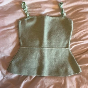 Grön topp från Zara - Säljer en stilren grön topp från Zara med smala axelband. Perfekt för varma dagar och kan enkelt matchas med olika outfits. Toppen har en enkel och elegant design.