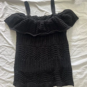 Svart stickad topp från Topshop - Säljer en svart stickad topp från Topshop med axelband och volangdetalj upptill. Toppen har en vit struktur. Passar bra till både jeans och kjol. 