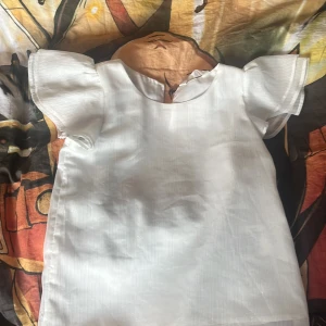 Vit blus från H&M - Säljer en söt vit blus från H&M med korta ärmar och en liten knappdetalj i nacken. I storlek 9-10 år men passar mig som har s i tröjor🩷