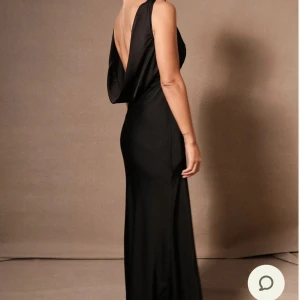 Svart långklänning med öppen rygg - Elegant svart långklänning med djup v-ringning och öppen rygg. Klänningen har en smickrande passform och är perfekt för festliga tillfällen. Tillverkad i ett mjukt och följsamt material som ger en lyxig känsla. Köpte för nån vecka sen till balen men har hittat en annan. Sååå fiinnn, prislapp och allt kvar