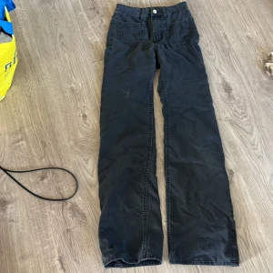 Svarta wide byxor från H&M Divided - Svarta byxor från H&M Divided med raka, vida ben och klassisk femficksdesign. Byxorna har hög midja och är tillverkade i ett mjukt bomullsmaterial. Perfekta för en avslappnad och trendig look.