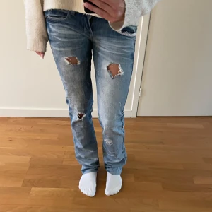 Miss Capri slitna blå jeans - Blå jeans från Miss Capri med slitna detaljer och hål på knäna. Raka ben och broderad bakficka med text. Klassisk femficksmodell med låg midja och cool tvätt. Säljer dessa favoriter då de tyvärr blivit för små för mig💗💗