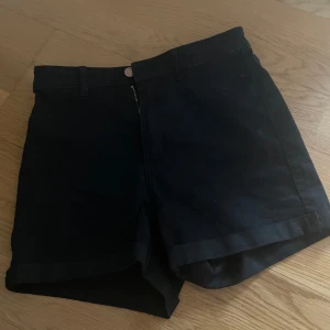 Svarta jeansshorts från &Denim - Svarta jeansshorts från &Denim med klassisk femficksdesign, bälteshällor och uppvikta benslut. Snygg och enkel modell som passar perfekt till sommaren. Dragkedja och knapp framtill. Perfekta för en chill och stilren look.